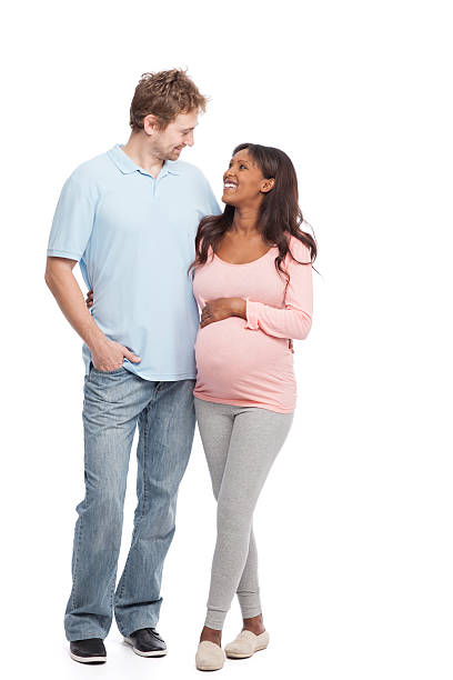 Future parent. Studio shot of mixed race pregnant couple looking each other with a smile. 8 months pregnant stock pictures, royalty-free photos & images