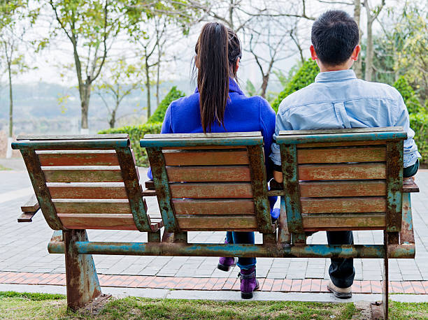 Rear view of mid adult couple on park bench.