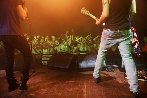 A crowd dancing at a rock concert while the band performs on stage. This concert was created for the sole purpose of this photo shoot, featuring 300 models and 3 live bands. All people in this shoot are model released.