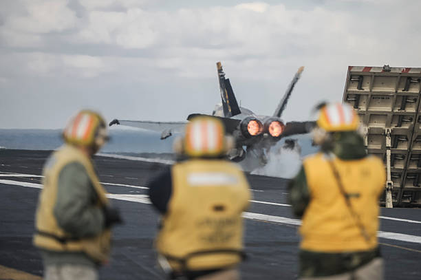 A navy helicopterr on the deck of an aircraft carrier near the bridge