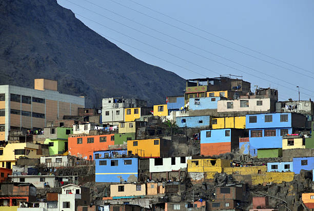 A favela where poor people leave in Lima, Peru, seen a hot summer day. In front a road with parked cars.