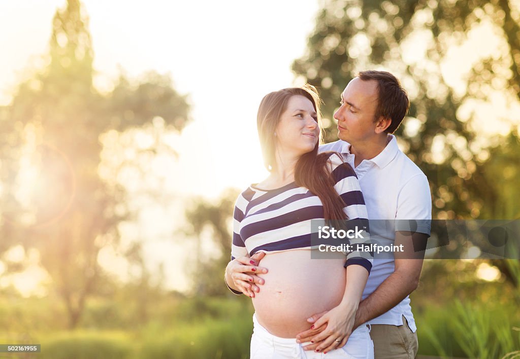 Pregnant couple Happy young pregnant couple hugging in nature Adult Stock Photo