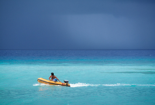 Man driving dingy boat at sea, Los Roques Archipelago, Venezuela