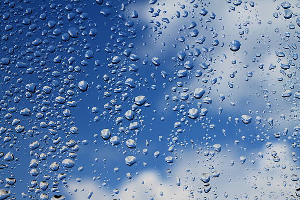 istock Rain drops on window with blue cloudy sky in background 502185892