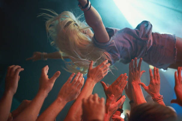 Diving into the crowd! A fan stage dives into the crowd at an awesome music concert. This concert was created for the sole purpose of this photo shoot, featuring 300 models and 3 live bands. All people in this shoot are model released. mosh pit stock pictures, royalty-free photos & images