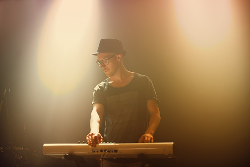 A young man playing a keyboard on stage at a music concert. This concert was created for the sole purpose of this photo shoot, featuring 300 models and 3 live bands. All people in this shoot are model released.