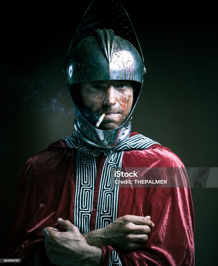bloody knight having a cigarette portrait of a bloody knight wearing an open helmet, after a photo session having a cigarette Humor Stock Photo
