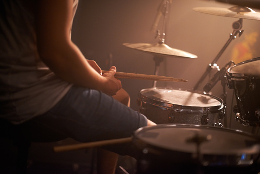 Cropped shot of a talented drummer hitting his drum skins hard at a gig. This concert was created for the sole purpose of this photo shoot, featuring 300 models and 3 live bands. All people in this shoot are model released.