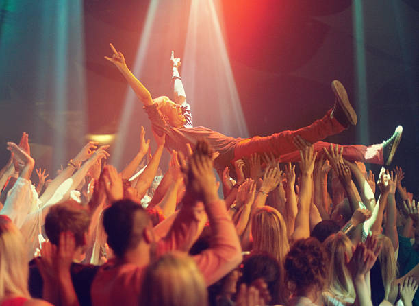 Lift me higher! A young man crowd surfing to his favorite band. This concert was created for the sole purpose of this photo shoot, featuring 300 models and 3 live bands. All people in this shoot are model released. concert mosh pit stock pictures, royalty-free photos & images