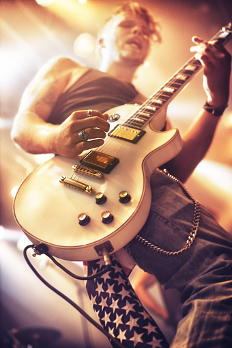 Low angle view of a guitarist playing at a gig. This concert was created for the sole purpose of this photo shoot, featuring 300 models and 3 live bands. All people in this shoot are model released.