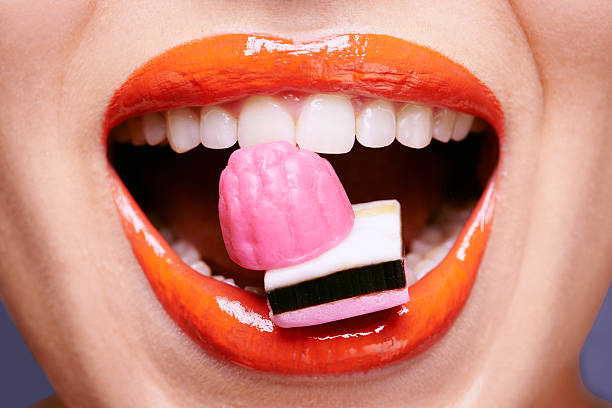 Licorice lips Cropped shot of a beautiful young woman eating liquorice sweetshttp://195.154.178.81/DATA/i_collage/pi/shoots/783619.jpg candy in mouth stock pictures, royalty-free photos & images