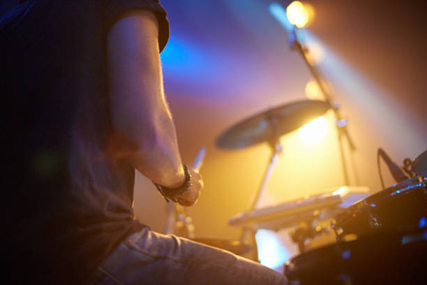 Smacking the skins hard! A young drummer rocking out on stage. This concert was created for the sole purpose of this photo shoot, featuring 300 models and 3 live bands. All people in this shoot are model released. drummer stock pictures, royalty-free photos & images