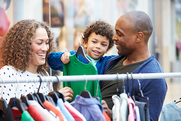familia buscando ropa en carril en el centro comercial - family with two children father clothing smiling fotografías e imágenes de stock