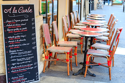 Street cafe in Paris - traditional wicker furniture and menu board exposed on the pavement, Paris, France 