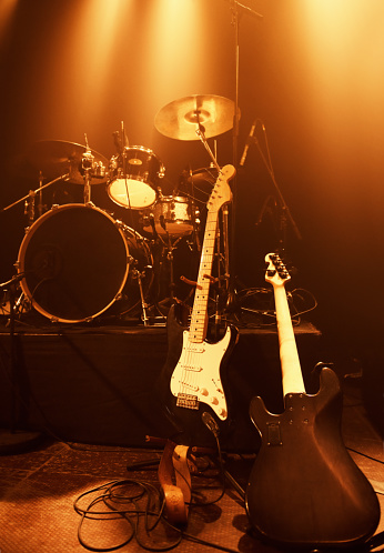 A drum kit and electric guitars standing on a stage before a concert.