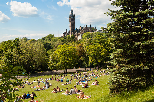  Glasgow, UK - June 8, 2013: View of Kelvingrove Park full of people enjoying the Scottish summer with the main building of Glasgow University on the top of the hill.