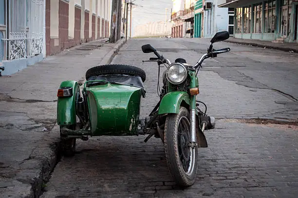 Green vintage motorcycle with sidecar parked on a street in Cienfuegos.