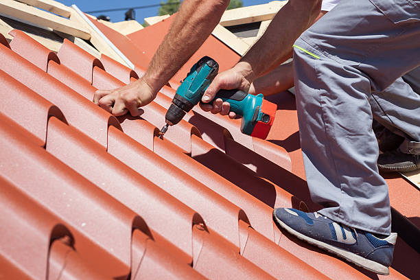 istock Worker on roof with electric drill installing red metal tile 502216384