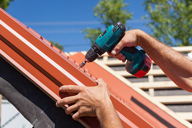 istock Worker on roof with electric drill installing red metal tile 502216536