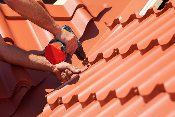 istock Worker on roof with electric drill installing red metal tile 502216556