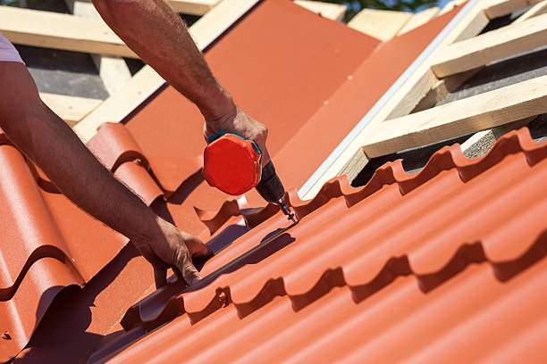 istock Worker on roof with electric drill installing red metal tile 502216572