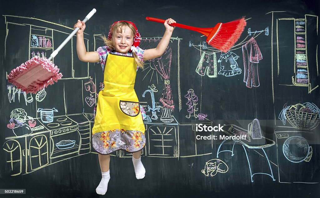 Cleaning lady kid Little girl jumping with a mop and a cleaning brush in hands on background of the drawing with chalk kitchen in the house Housework Stock Photo