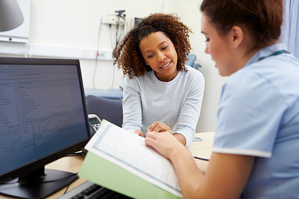 Nurse Discussing Test Results With Patient Nurse Discussing Test Results With Patient In Office Looking At Documents doctor general practitioner stock pictures, royalty-free photos & images