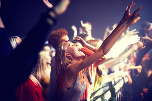 A group of people standing with their arms raised at a concert. This concert was created for the sole purpose of this photo shoot, featuring 300 models and 3 live bands. All people in this shoot are model released.