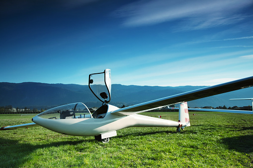 Glider airplane with open canopy at grass runway