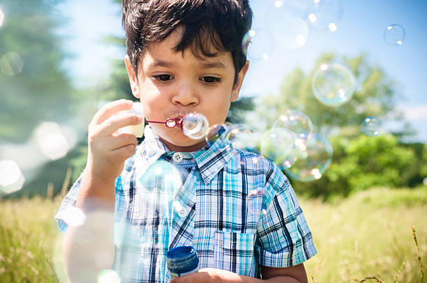 szczęśliwy mały chłopiec wieje pęcherzyki powietrza na zewnątrz - bubble wand child blowing asian ethnicity zdjęcia i obrazy z banku zdjęć