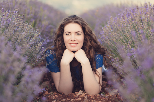 Beautiful caucasian woman lying in the purple field of lavender flowers.