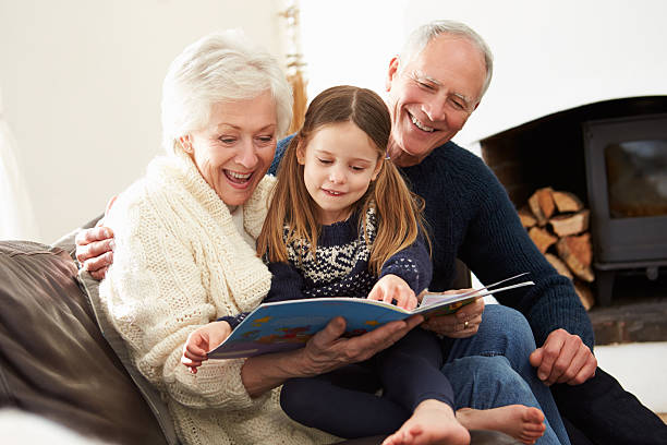großeltern mit enkelin buch zusammen zu hause lesen - grandparent family reading inside of stock-fotos und bilder