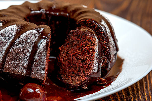 istock Chocolate cake with glaze, cherry on white plate 502245604