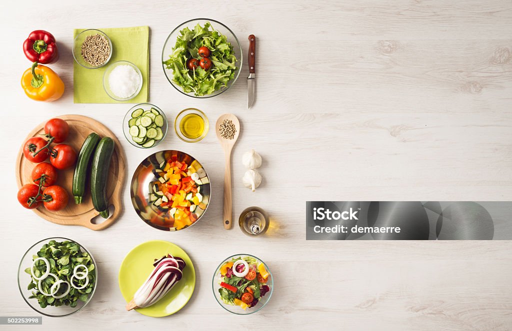 Healthy eating and food preparation at home Healthy eating concept with fresh vegetables and salad bowls on kitchen wooden worktop, copy space at right, top view Kitchen Counter Stock Photo