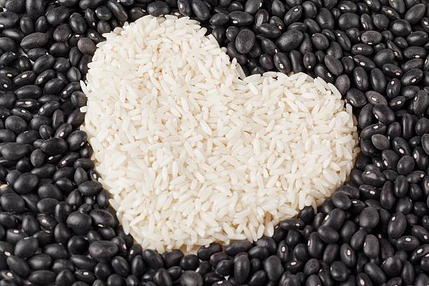 heart shape rice grains isolated on the dark beans stock photo
