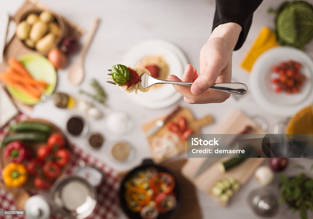 Chef at work cooking pasta Chef in the kitchen holding a fork with spaghetti, tomato sauce and basil, food ingredients and utensils on background, top view Food Stock Photo