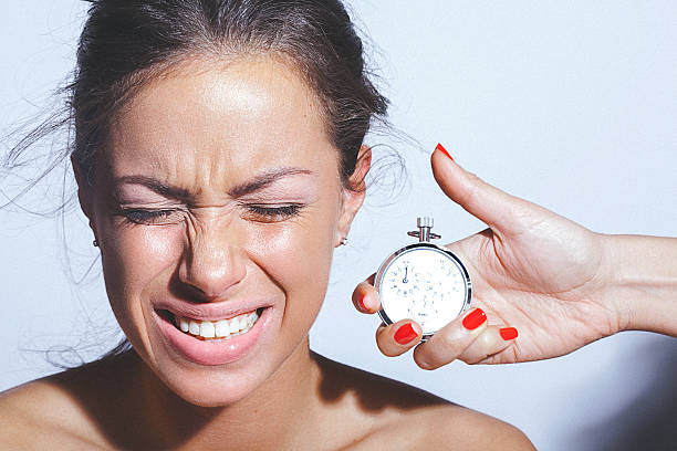 giovane donna facendo fare le boccacce accanto a mano che tiene il cronometro - male beauty beauty hairstyle shirtless foto e immagini stock