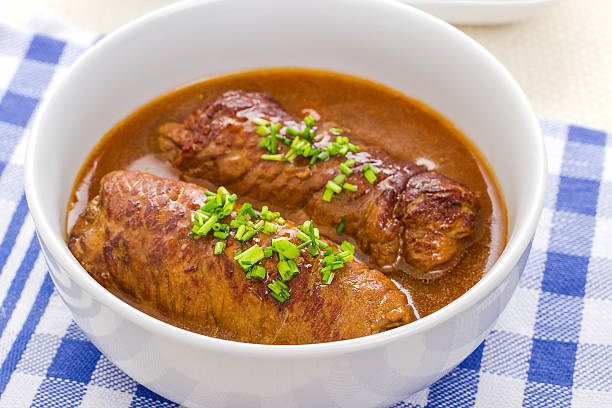 Two roulades beef in bowl with sauce, close up, soft focus