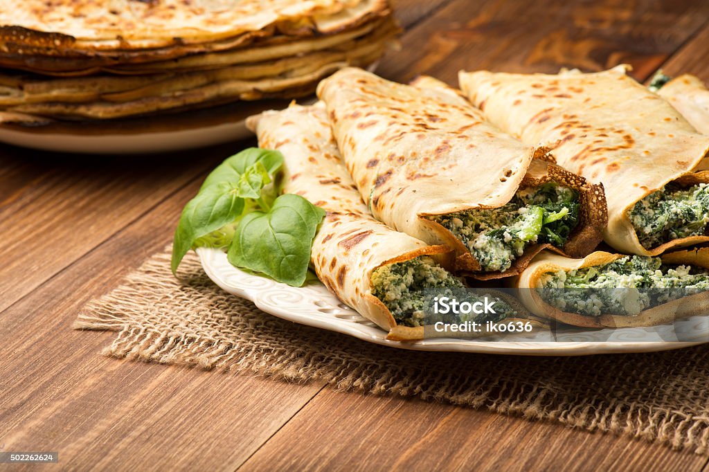 Pancakes filled  with spinach and cheese  on the wooden surface. Spinach Stock Photo