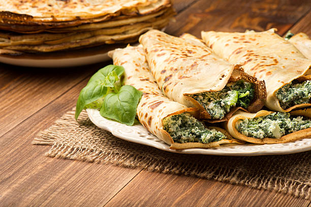 Pancakes filled  with spinach and cheese  on the wooden surface. stock photo