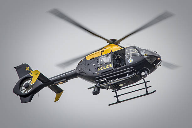 Fairford, UK - July 13, 2014: A Eurocopter EC135 helicopter of the UK's National Police Air Service flies over an air show in Gloucestershire, England, with a crew member taking photographs from the open side door. 