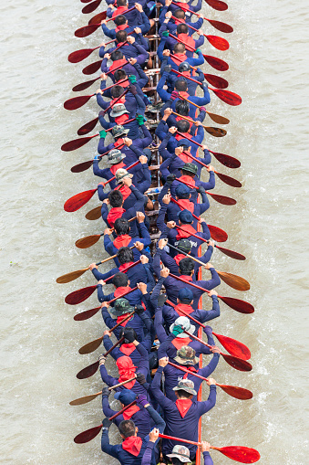 Bangkok, Thailand - December 12, 2010: Aerial view of Male, Thai rowers race in their blue jerseys during a dragon boat on the Chao Phraya River in Bangkok. In this traditional crafted wooden boat can accommodate up to 100 participants with their paddles place. The boats can reach a length of 25 meters.