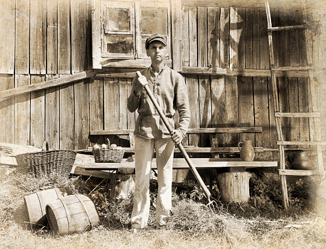 Male farmer holding a pitchfork. Intentional 1900's style post processing emulation..
