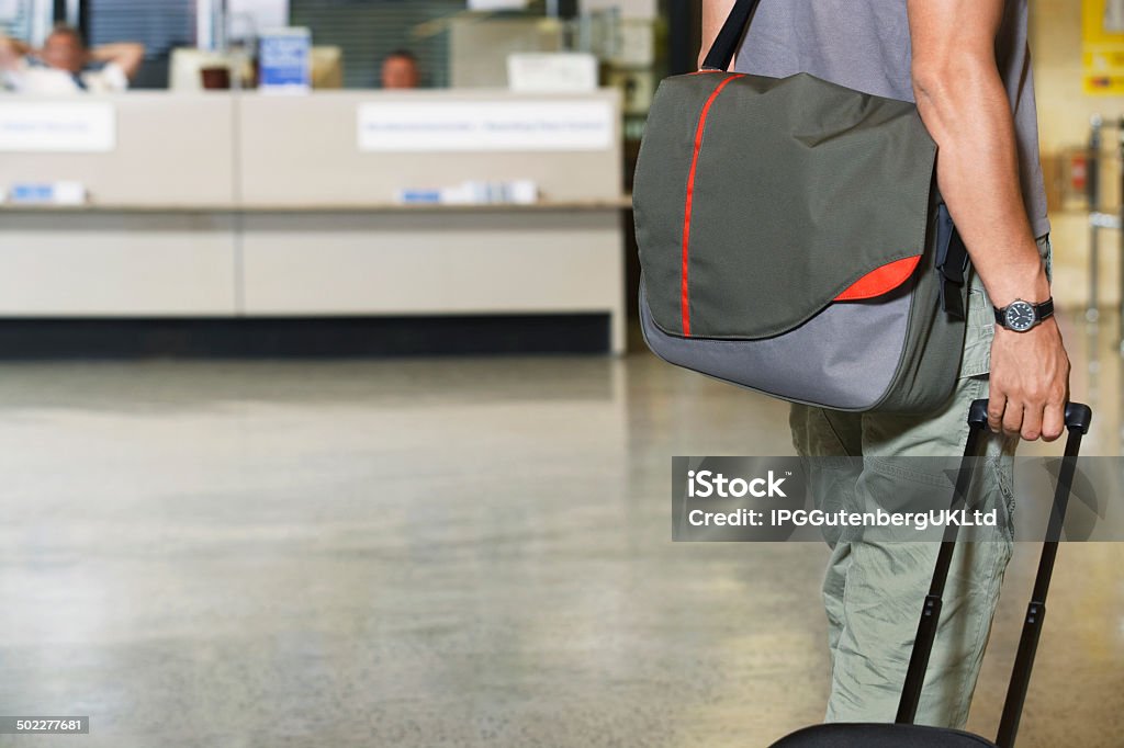Male Traveler With Luggage In Lobby Closeup side view midsection of a male traveler with bags at the airport Airport Stock Photo
