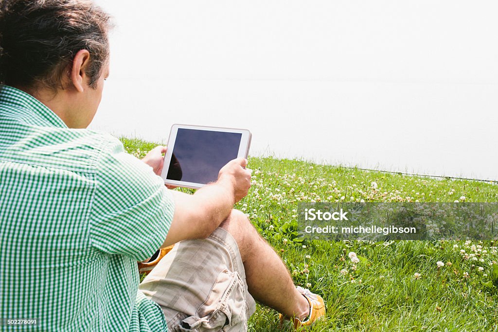 Uomo utilizzando un Computer Tavoletta digitale all'aperto in Natura - Foto stock royalty-free di Abbigliamento casual