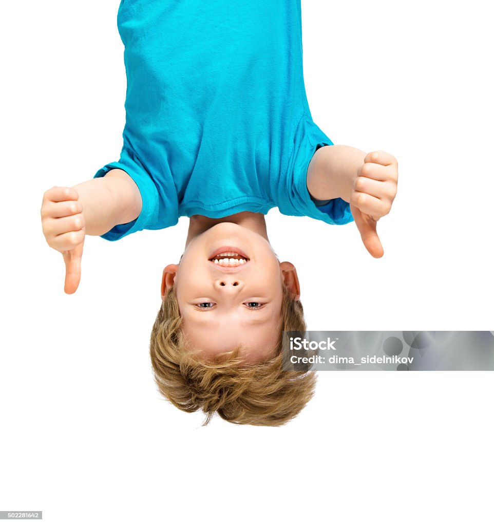 Handsome little boy hanging upside down Funny photo of handsome little boy hanging upside down on white background. Boy smiling and showing thumbs up Child Stock Photo