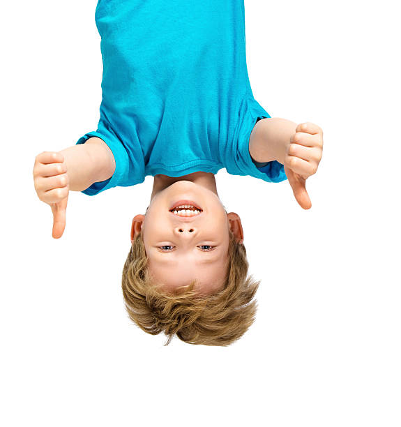 Handsome little boy hanging upside down Funny photo of handsome little boy hanging upside down on white background. Boy smiling and showing thumbs up upside down stock pictures, royalty-free photos & images