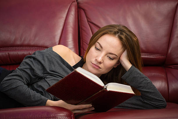 istock Attractive young woman resting on sofa and reading a book 502285978