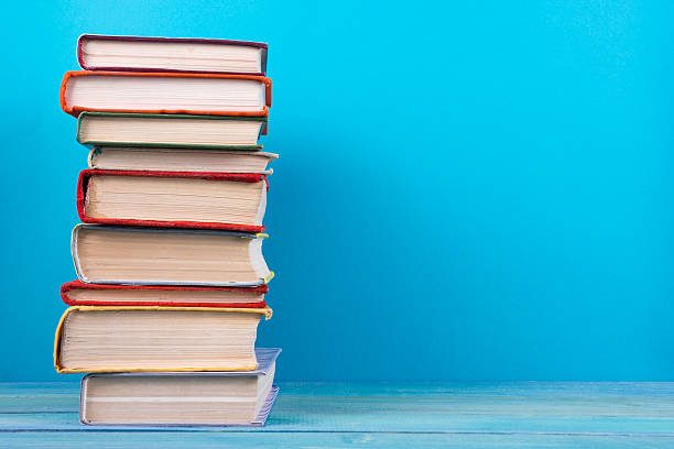 istock Stack of colorful hardback books, open book on blue background 502289344