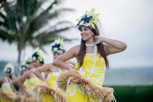 A group of women are doing a traditional Hawaiian dance during a luau for tourists on vacation.